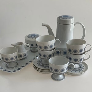K&ouml;nnte beinhalten: Ein Set aus wei&szlig;en Porzellan-Teetassen und Untertassen mit einem blauen und wei&szlig;en geometrischen Muster. Das Set enth&auml;lt eine Teekanne, eine Milchk&auml;nnchen und eine Zuckerdose.