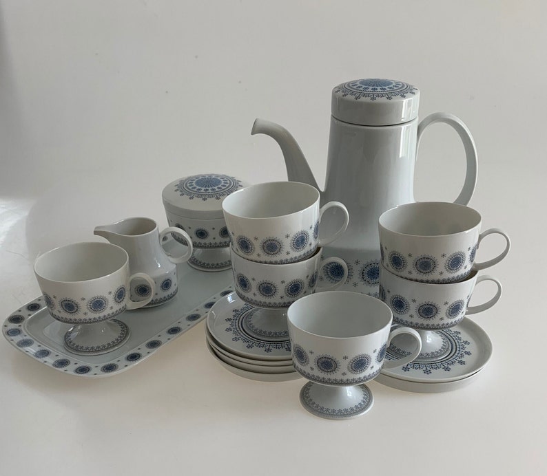 K&ouml;nnte beinhalten: Ein Set aus wei&szlig;en Porzellan-Teetassen und Untertassen mit einem blauen und wei&szlig;en geometrischen Muster. Das Set enth&auml;lt eine Teekanne, eine Milchk&auml;nnchen und eine Zuckerdose.
