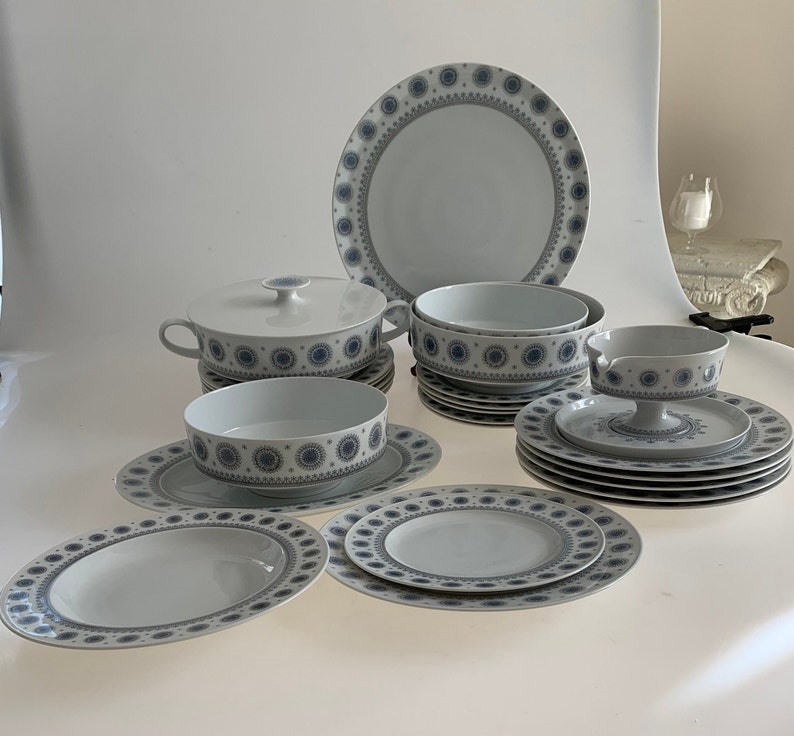 K&ouml;nnte beinhalten: Ein Set aus wei&szlig;em Porzellan-Geschirr mit einem blauen und grauen Blumenmuster. Das Set enth&auml;lt eine gro&szlig;e Platte, Schalen und Teller.