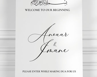 Pode incluir: Uma placa branca com caligrafia preta que diz "بسم الله الرحمن الرحيم" e "WELCOME TO OUR BEGINNING". Abaixo do texto estão os nomes "Anenar & Imane" em escrita cursiva. A placa também inclui o texto "PLEASE ENTER WHILE MAKING DUA FOR US".