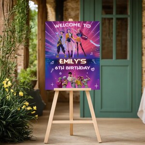 May include: A wooden easel displays a colorful birthday sign. The sign reads "WELCOME TO EMILY'S 6TH BIRTHDAY" with a vibrant graphic of people and musical notes. The background is a gradient of purple and pink.