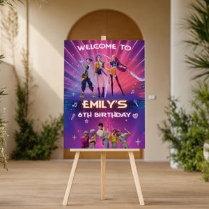May include: A wooden easel displays a vibrant birthday party sign. The sign reads "WELCOME TO" above a group of animated characters, with "EMILY'S 6TH BIRTHDAY" in bold letters. The background is a gradient of purple and pink.