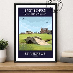Pode incluir: Uma impressão emoldurada com uma cena de campo de golfe com uma ponte de pedra e edifícios sob um céu azul. O texto diz "150th Open Championship" e "St Andrews July 2022". A impressão está em uma moldura preta.
