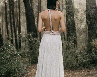 May include: A woman wearing a white lace wedding dress with a pink halter top in a forest setting.