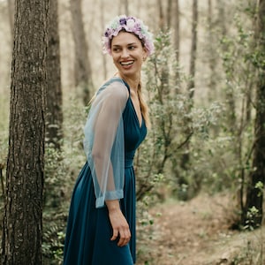 Könnte beinhalten: Eine Frau in einem blaugrünen Kleid mit einem hellblauen, durchsichtigen Überwurf und einer Blumenkrone. Sie steht in einem Wald.
