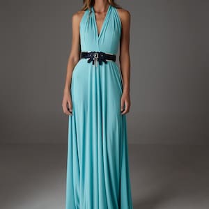 Könnte beinhalten: Ein hellblaues Maxikleid mit einem Halterneck und einem schwarzen Gürtel mit einer dekorativen Schnalle. Das Kleid hat eine fließende, A-förmige Silhouette.