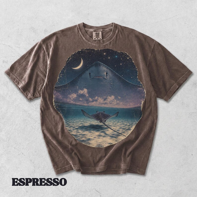 Pode incluir: Uma t-shirt castanha de manga curta com um gr&aacute;fico circular de uma raia a nadar num oceano pouco profundo sob um c&eacute;u noturno com uma lua crescente e estrelas. A palavra ESPRESSO est&aacute; impressa em letras mai&uacute;sculas pretas abaixo.