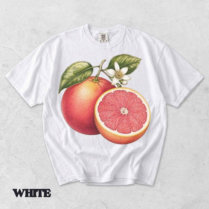 Puede incluir: Una camiseta blanca de manga corta con una ilustraci&oacute;n bot&aacute;nica detallada de un pomelo entero, un pomelo cortado por la mitad con pulpa rosa, hojas verdes y una peque&ntilde;a flor blanca centrada en la parte delantera de la prenda.
