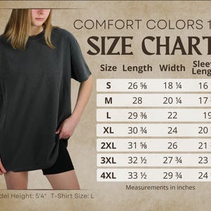 Pode incluir: Uma tabela de tamanhos Comfort Colors 1717 exibindo medidas em polegadas para tamanhos de S a 4XL. A tabela lista comprimento, largura e comprimento da manga. Uma camiseta cinza escuro &eacute; exibida com altura do modelo 5'4" e tamanho L.