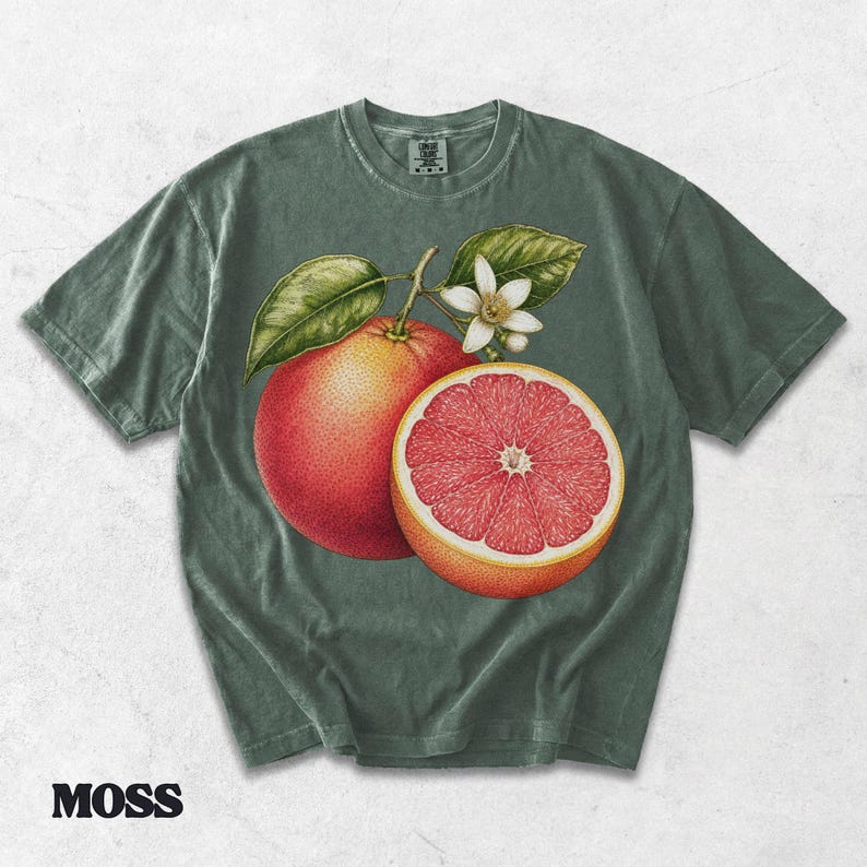 Puede incluir: Una camiseta de manga corta color verde musgo con una ilustraci&oacute;n bot&aacute;nica de un pomelo entero y otro cortado por la mitad, junto a una flor blanca y hojas verdes en el centro. La prenda cuenta con un cuello redondo y acabado vintage.