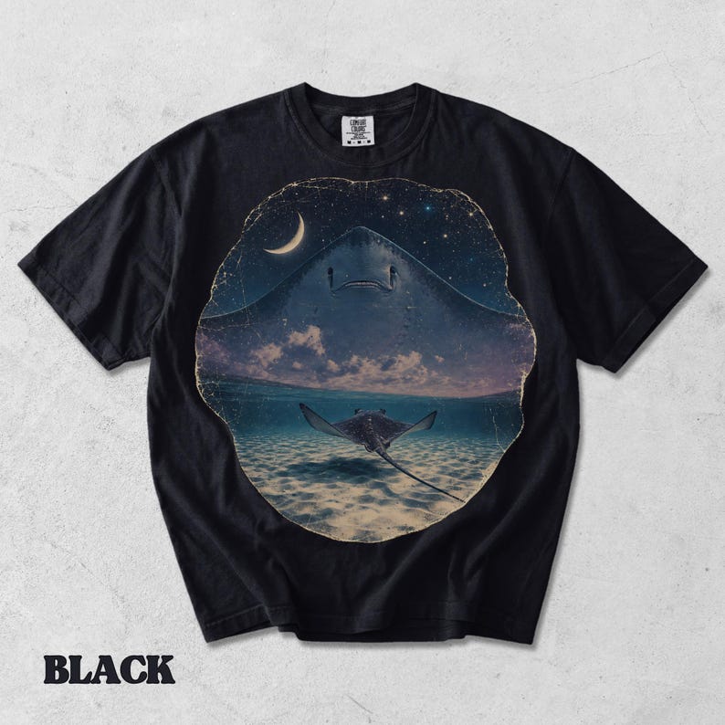 Pode incluir: Uma t-shirt preta de manga curta com uma estampa gr&aacute;fica circular. O design mostra a silhueta de uma raia grande contra um c&eacute;u noturno estrelado com uma lua crescente, acima de uma raia menor a nadar em &aacute;gua do mar l&iacute;mpida.