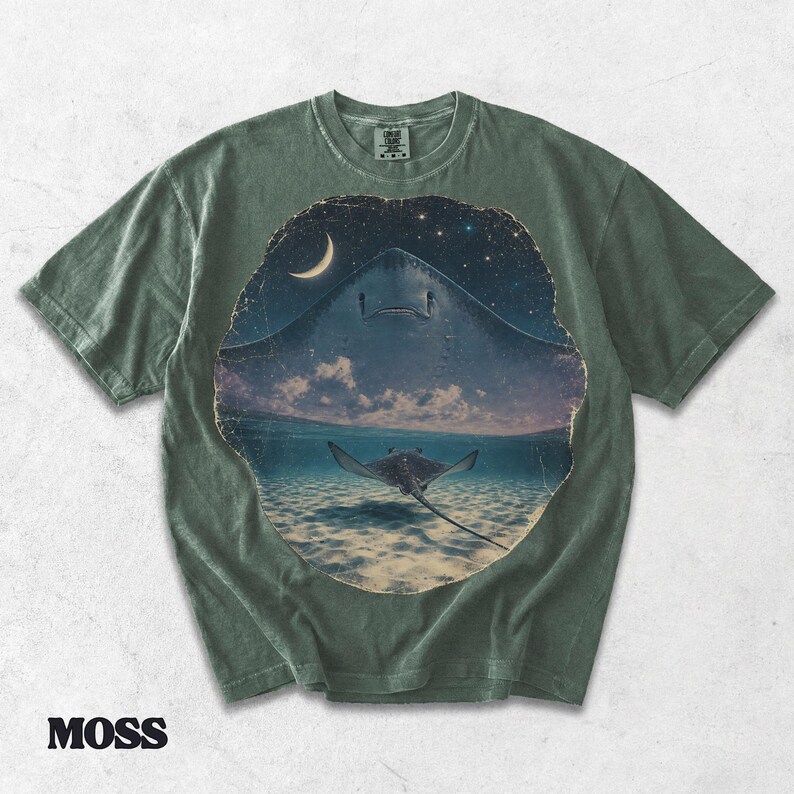 Pode incluir: Uma t-shirt de manga curta verde musgo com uma impress&atilde;o gr&aacute;fica circular. O design mostra a silhueta de uma raia grande contra um c&eacute;u estrelado acima de uma raia menor a nadar em &aacute;gua l&iacute;mpida com uma lua crescente vis&iacute;vel.