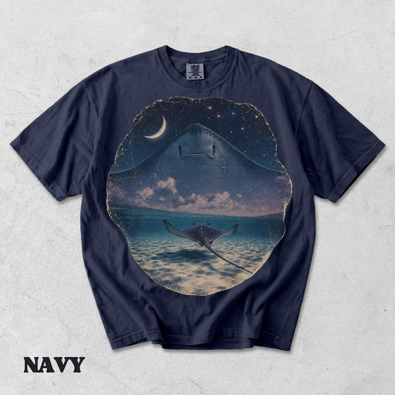 Pode incluir: Uma t-shirt de manga curta azul-marinho com uma estampa gr&aacute;fica circular. O design mostra a silhueta de uma raia grande contra um c&eacute;u noturno estrelado com uma lua crescente e uma raia menor nadando na &aacute;gua do oceano abaixo.