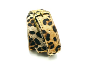 May include: A brown and black leopard print belt with a gold metal buckle.