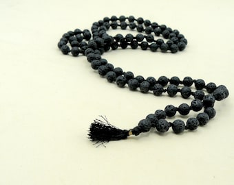 May include: A black lava rock mala bead necklace with a black tassel. The beads are round and have a rough texture.