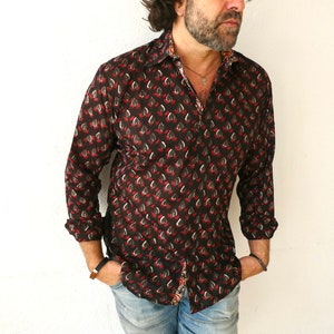 May include: A long-sleeved shirt with a black background and a red and white floral pattern. The shirt has a button-down collar and a relaxed fit.