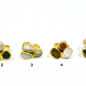 Puede incluir: Seis anillos de oro con piedras de diferentes colores. Cada anillo tiene tres piedras engastadas en forma de triángulo. Las piedras son turquesa, blanca, marrón, ojo de tigre, verde y gris.
