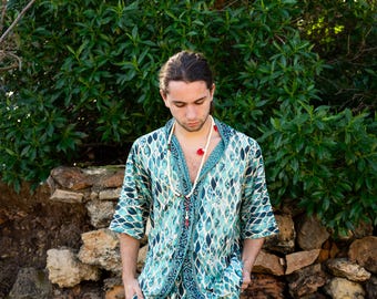 May include: A person wearing a blue and white patterned shirt and matching shorts. The shirt has a short sleeve and a collar. The person is wearing a white beaded necklace with red beads.
