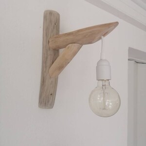 May include: A rustic wooden wall sconce with a single light bulb hanging from it. The sconce is made of driftwood and has a natural, weathered finish.