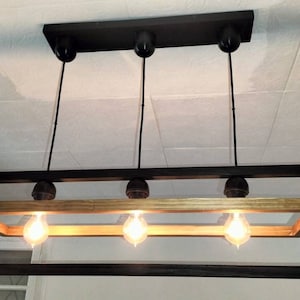 May include: A black rectangular frame chandelier with four light bulbs. The frame is made of wood with a natural finish and has a black metal outer frame.