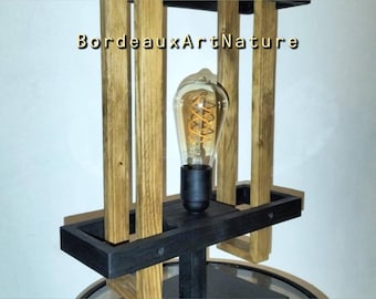 May include: A lamp featuring a central Edison-style light bulb with a visible glowing filament, surrounded by vertical natural wood slats and a black base. The text BordeauxArtNature is printed in the center of the wooden structure.