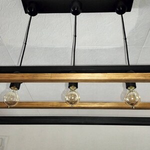 May include: A rectangular black and gold framed chandelier with three light bulbs.