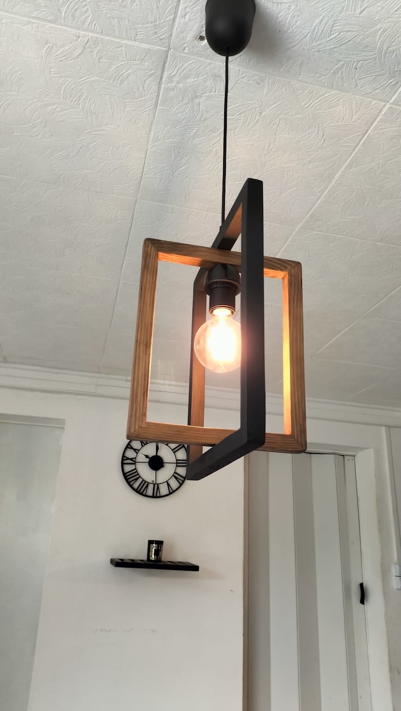 May include: A wooden and black metal pendant light fixture with a single light bulb. The light fixture is hanging from a ceiling with a white textured surface.
