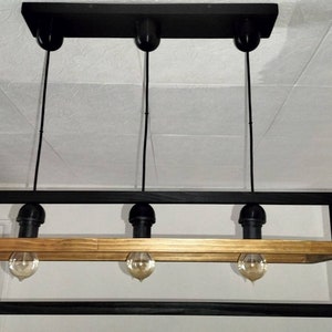 May include: A black metal frame with a wooden shelf and four hanging light bulbs. The light fixture is suspended from the ceiling.