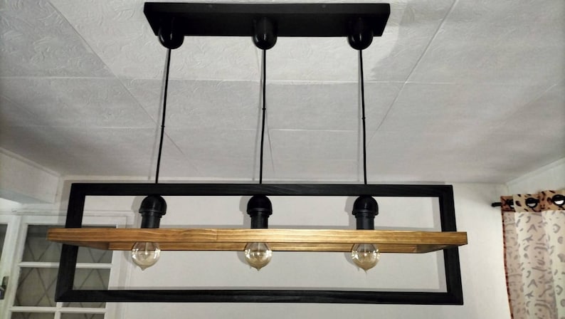 May include: A black metal frame with a wooden shelf and four hanging light bulbs. The light fixture is suspended from the ceiling.