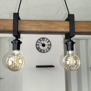May include: A rustic wooden and metal light fixture with two Edison bulbs hanging from a wooden beam. The fixture is suspended from the ceiling with black cords.