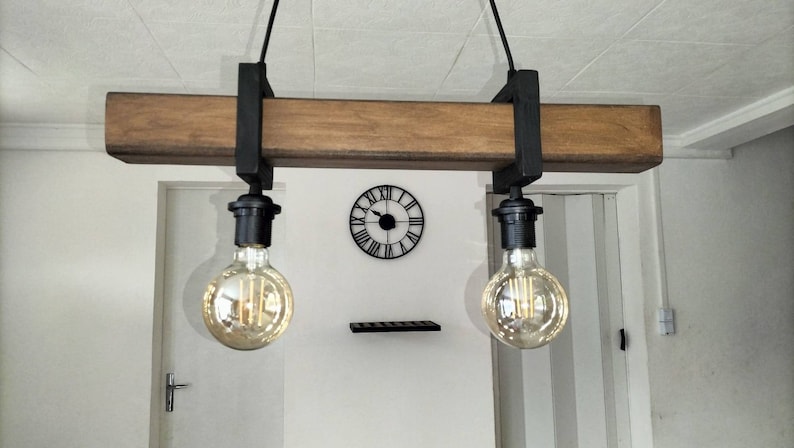 May include: A rustic wooden and metal light fixture with two Edison bulbs hanging from a wooden beam. The fixture is suspended from the ceiling with black cords.