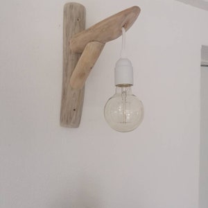 May include: A wall-mounted light fixture made from driftwood with a single light bulb hanging from it.