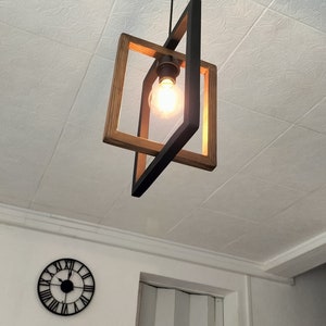 May include: A black and wood framed pendant light with a single light bulb hanging from the ceiling.