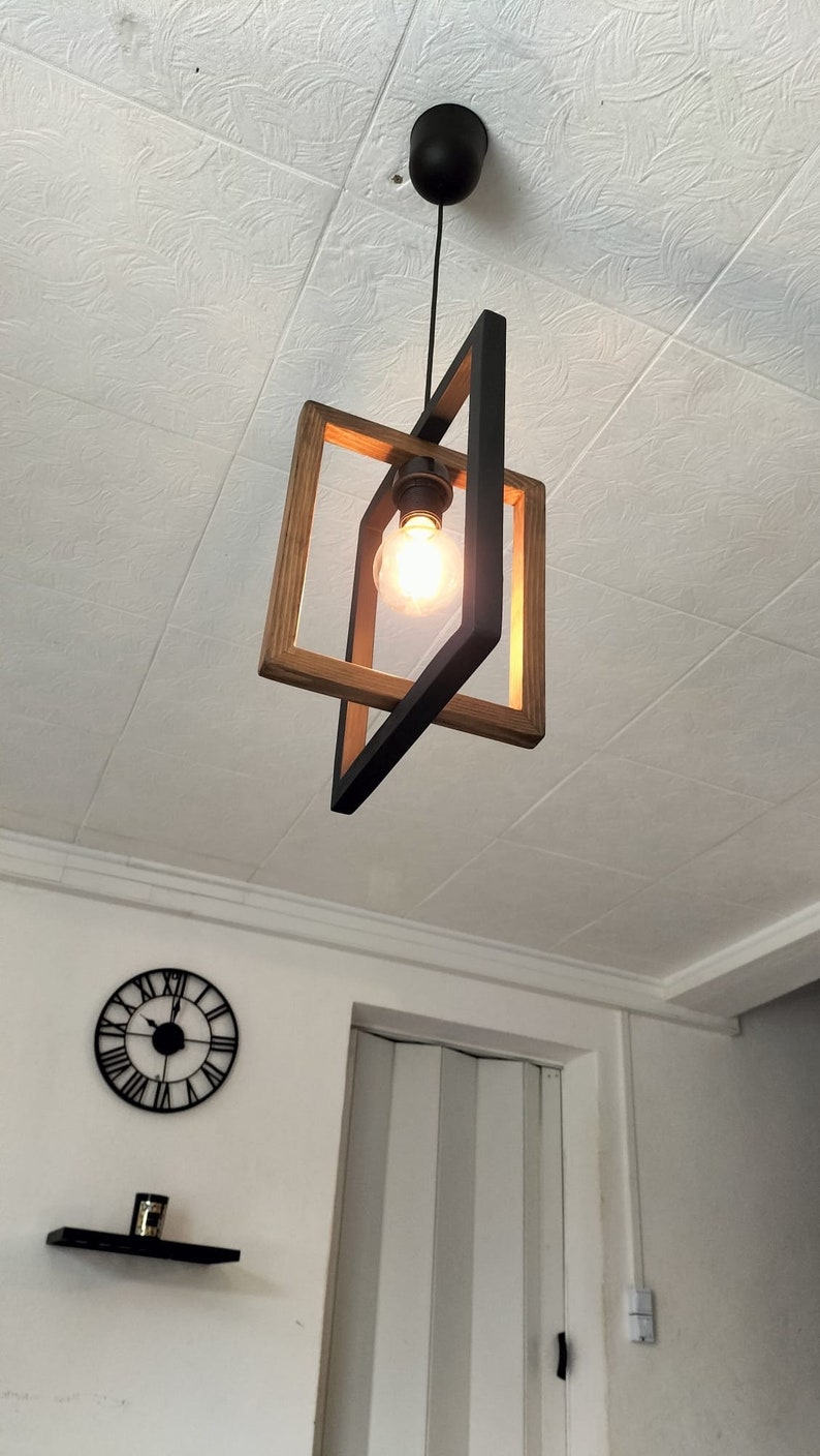 May include: A black and wood framed pendant light with a single light bulb hanging from the ceiling.