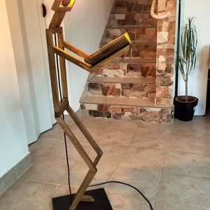 Peut inclure: Un lampadaire en bois en forme de personne lisant un livre. La lampe a une ampoule chaude et un cordon noir.