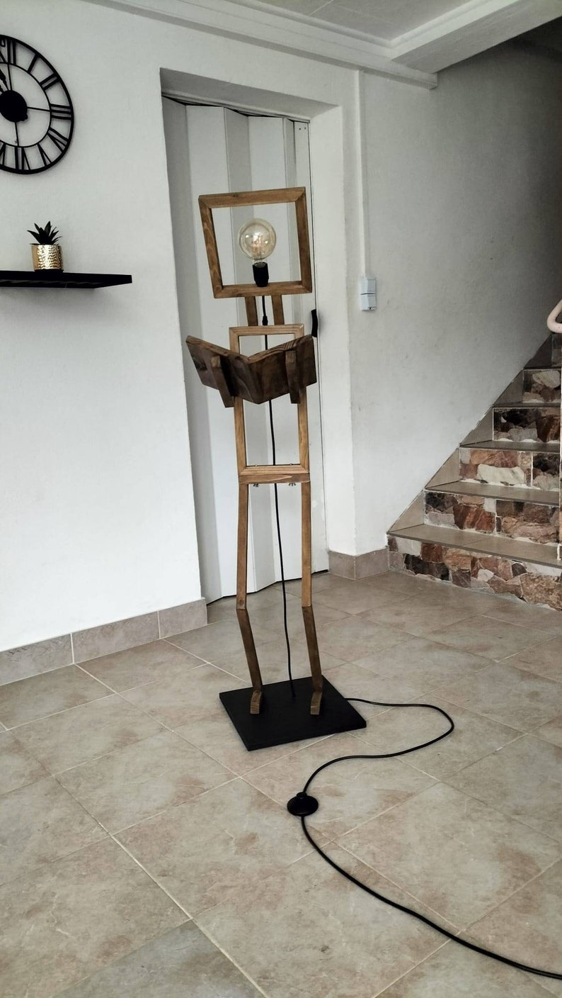 Peut inclure: Un lampadaire en bois en forme de personne tenant un livre. La lampe a une ampoule dans la t&ecirc;te et un cordon noir.