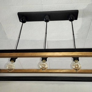 May include: A rectangular wood and metal chandelier with four light bulbs. The frame is made of black metal with a wood accent.