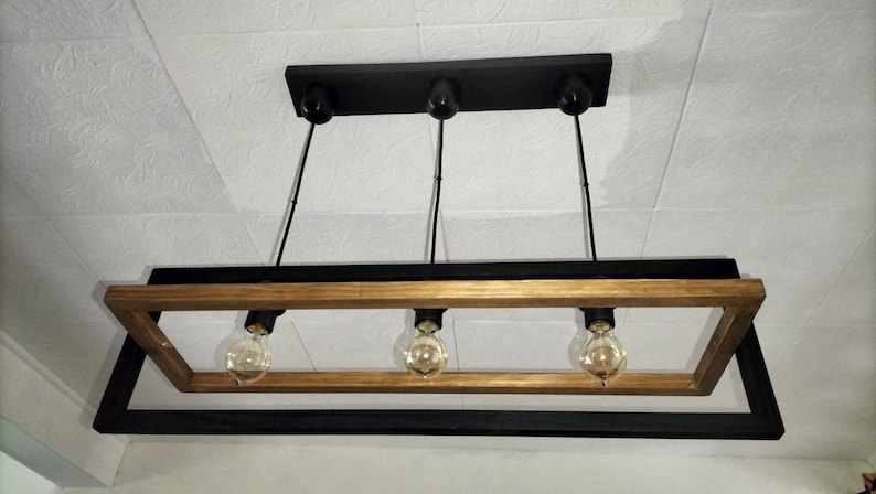May include: A rectangular wood and metal chandelier with four light bulbs. The frame is made of black metal with a wood accent.