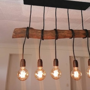 Puede incluir: Una lámpara de araña rústica de rama de madera con seis bombillas de alambre negro suspendidas. Las bombillas son de estilo Edison y emiten un brillo cálido.