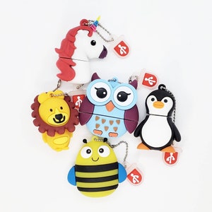 May include: A collection of five silicone USB flash drives shaped like animals, including a white unicorn with a red mane, a yellow lion, a blue and purple owl, a black and white penguin, and a yellow and black bee, each with a small metal chain.