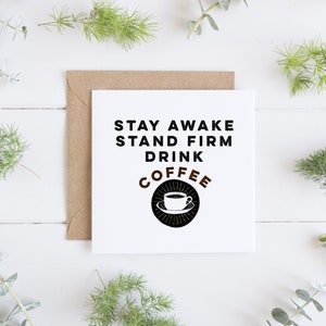May include: White card with black text that reads "Stay Awake Stand Firm Drink Coffee" with a black and white illustration of a coffee cup in a circle with brown accents.