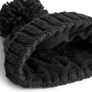 Peut inclure: Bonnet noir en tricot avec un pompon moelleux et une doublure en polaire. Le bonnet est pli&eacute; en deux pour montrer la doublure.