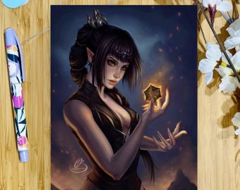 May include: An art print of a woman with dark hair and green eyes holding a glowing star. The artwork is on a wooden surface with confetti and a floral pen. The woman is wearing a dark outfit.