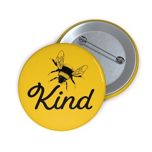 May include: A yellow button featuring a black bumblebee and the word "Kind" in black script.