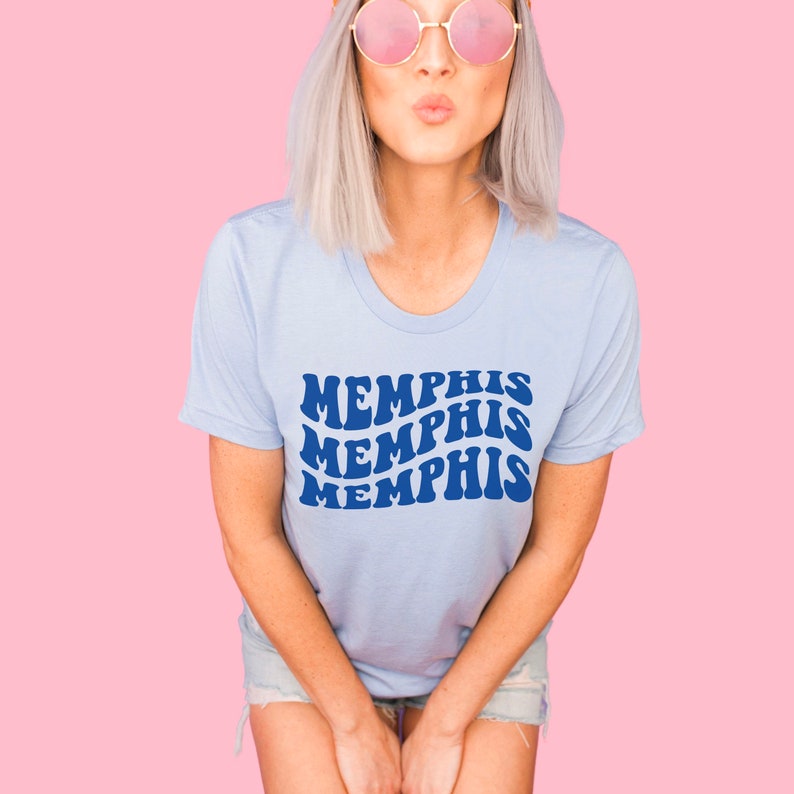 May include: A light blue t-shirt with a blue graphic that says "MEMPHIS" three times in a retro font.