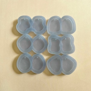 May include: Six pairs of clear silicone molds for making earrings. Each mold has two cavities shaped like a teardrop with a small hole at the top for attaching a jump ring.