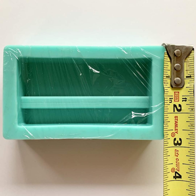 May include: A turquoise silicone mold with two rectangular cavities, measuring 2 inches in length. The mold is wrapped in clear plastic.