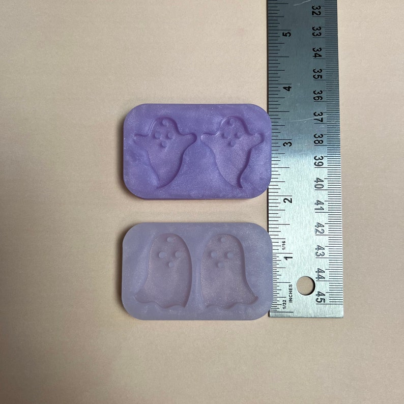 May include: Two purple silicone molds for making ghost-shaped treats. Each mold has two ghosts with a dotted pattern.