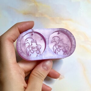 May include: A two-part silicone mold for resin casting featuring a design of two squirrels holding acorns. The mold is a light purple color and has a shiny finish.