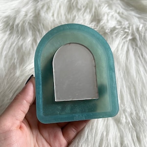 May include: A light blue silicone tray with a semi-circular cutout. The tray has a frosted finish and the text "ellaful" is printed on the bottom.